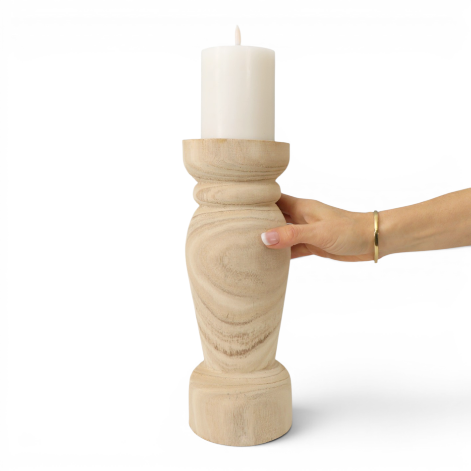 Hand holding the Corinth paulownia wood candle holder with an ivory pillar candle to show its scale